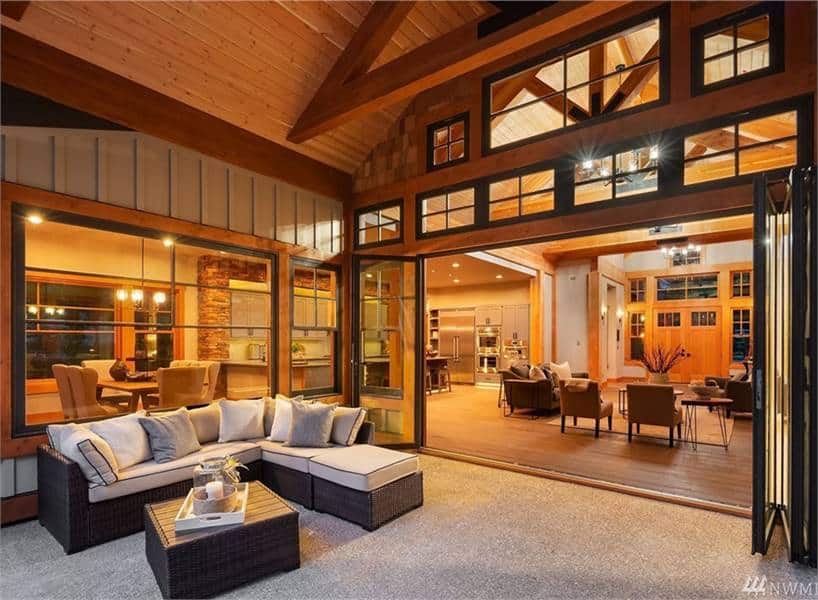 The outdoor living space is filled with a wicker coffee table and an L-shaped sofa topped with beige cushions and neutral pillows.