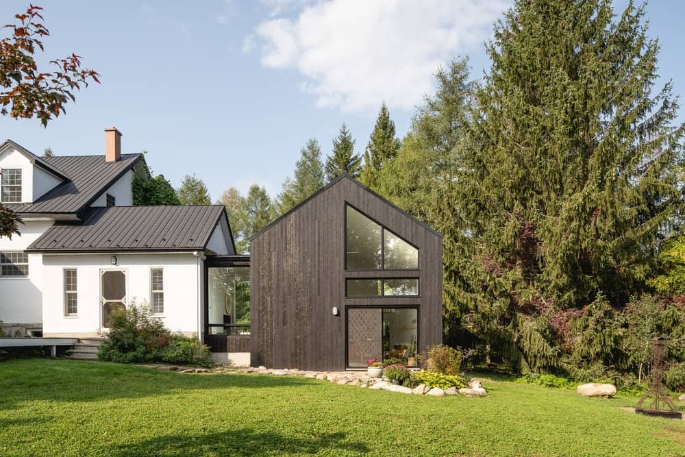 This is a look at the back of the house with a large extension structure that houses the art studio with simple dark tones and glass walls.