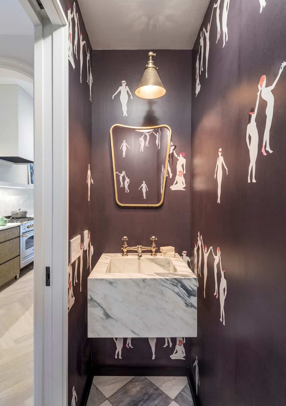 This is the small powder room with a floating white marble sink surrounded by a dark patterned wallpaper.