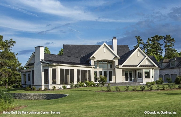 View of the house from the backyard showing the expansive lush lawn complementing the rear porch.