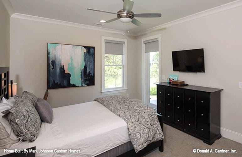 Another bedroom with carpet flooring, black furnishings, and beige walls adorned with an abstract painting.