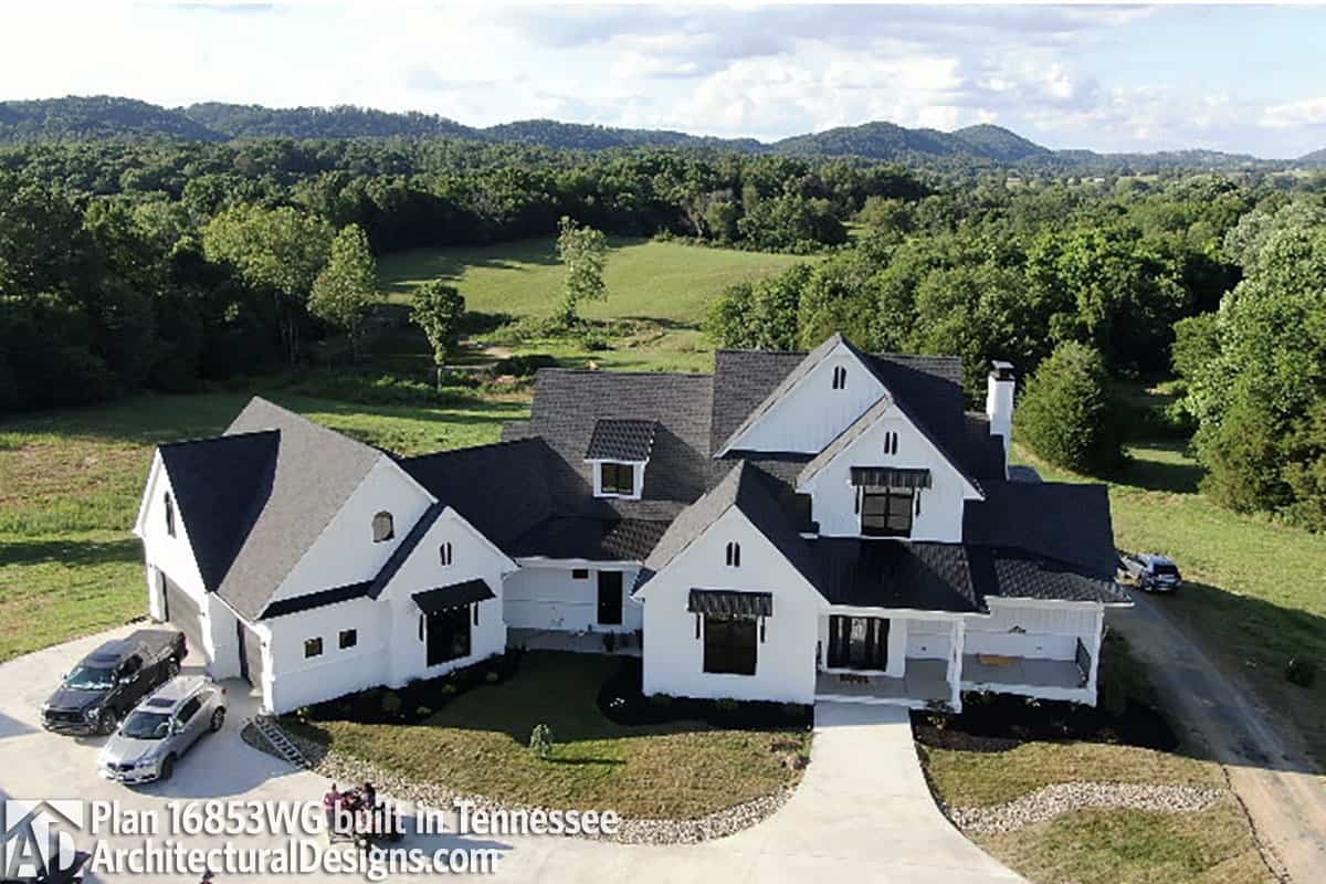 Aerial view of the house showing the black tiled roofs and white siding.