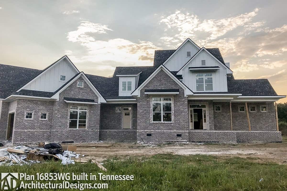 An alternate exterior with stone and vertical lap siding, metal awnings, and white framed windows.