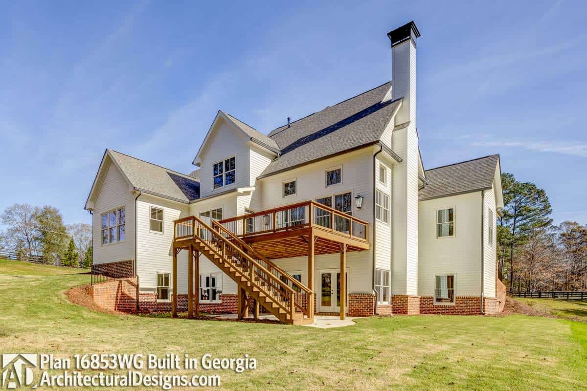 A straight wooden staircase complements the rear deck of this farmhouse.