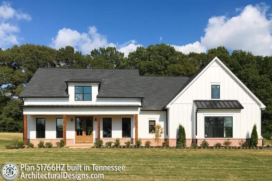 Front exterior view showing the board and batten siding, brick bases, and a wide porch lined with rustic columns.