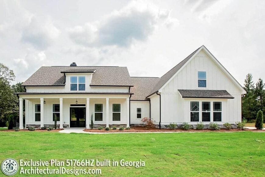 The home facade is adorned by a large gable, shed dormer, and decorative white columns.
