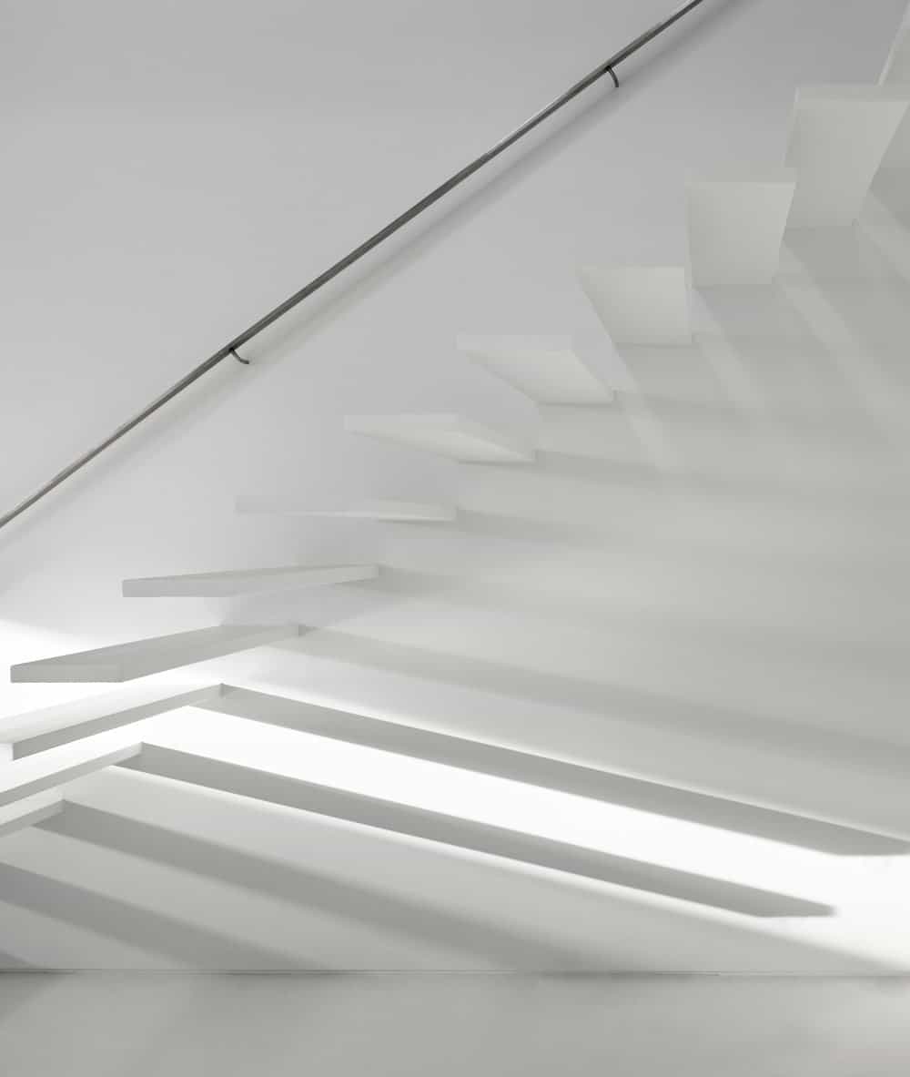 This is a closer look at the modern white staircase that has white steps blending with the white wall.