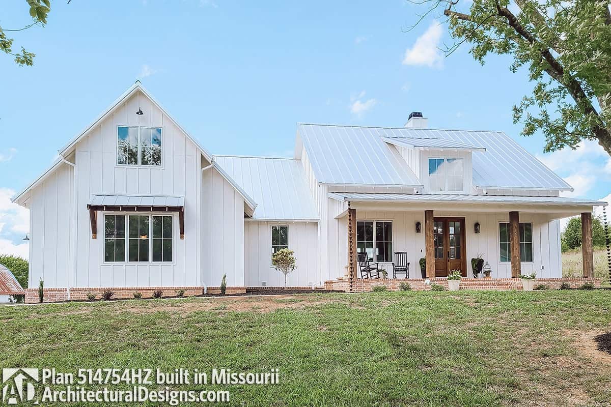 Classic farmhouse exterior with white siding, a dormer window, and a covered porch lined with wooden columns.