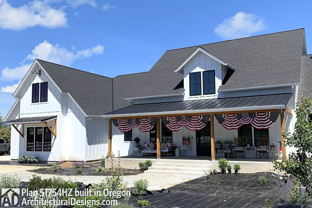 Rustic columns, a large dormer, and decorative flags adorn this home's facade.