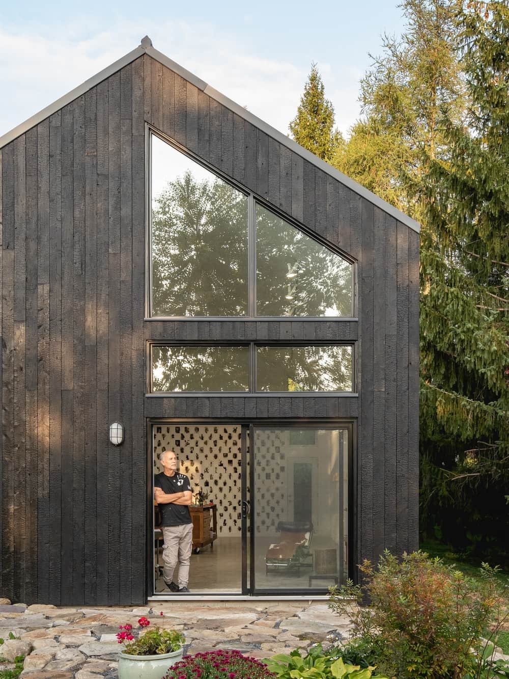This is a close look at the house extension with dark wooden exterior walls that is complemented by the glass walls.