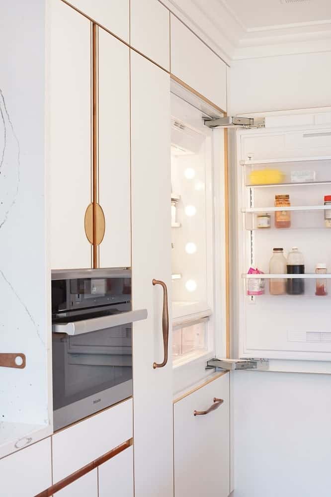 On the other side is the fridge with doors that blend seamlessly with the beige cabinetry of the kitchen.