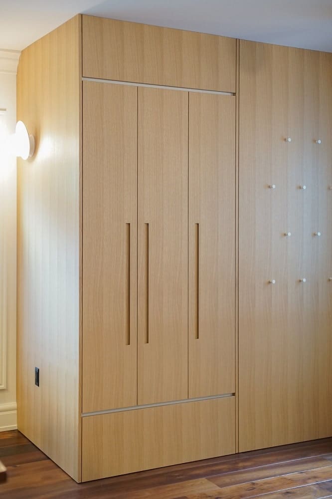 This is a farther view of the wooden cabinet featuring other carved handles and a somewhat floating design at the bottom.