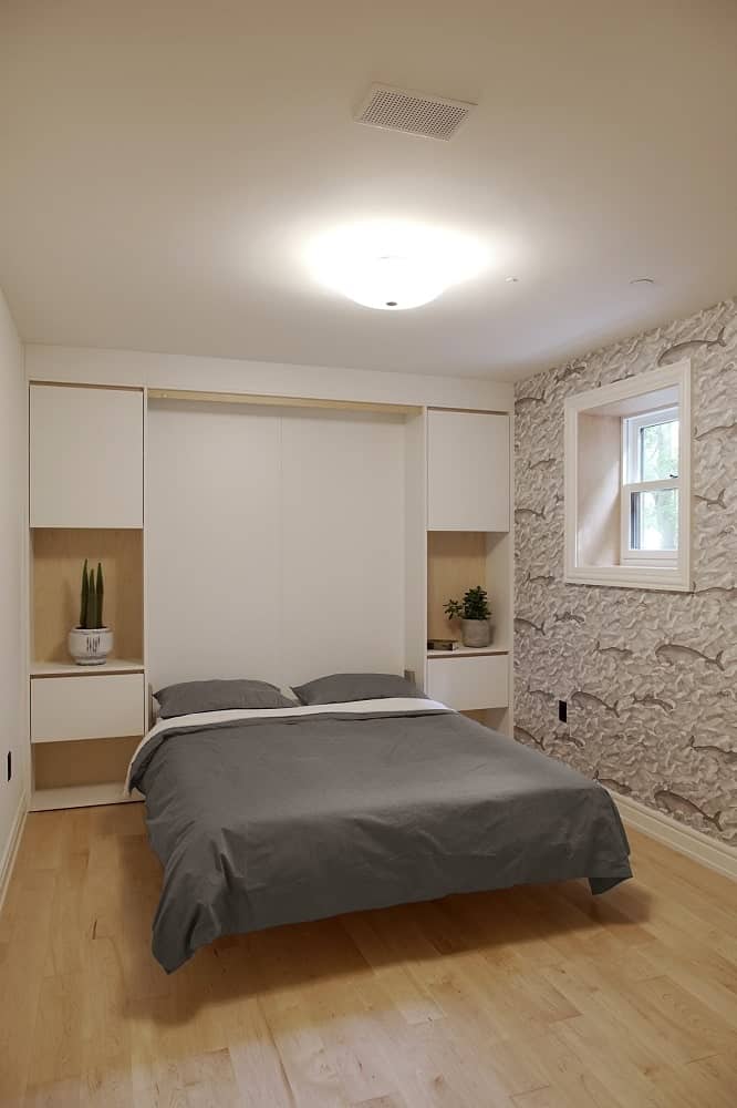 This is the bedroom with a simple design to its beige ceiling, beige wall and hardwood flooring making the gray bed stand out.
