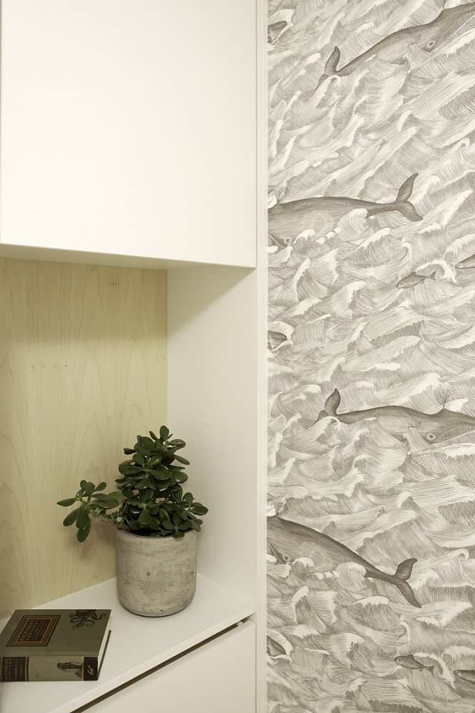 This is a close look at the built-in shelf on the side of the Murphy bed adorned with a potted plant. This view also shows the wallpaper on the side wall.