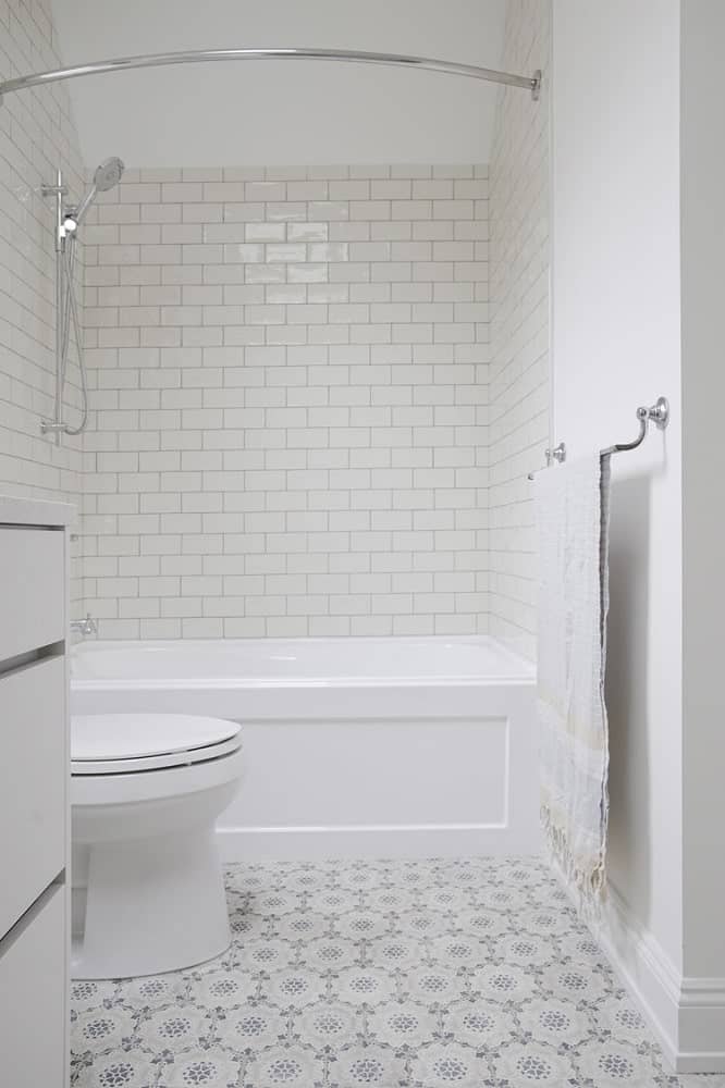 This is a look at the toilet and bathtub of the bathroom that is adorned with white subway tiles.