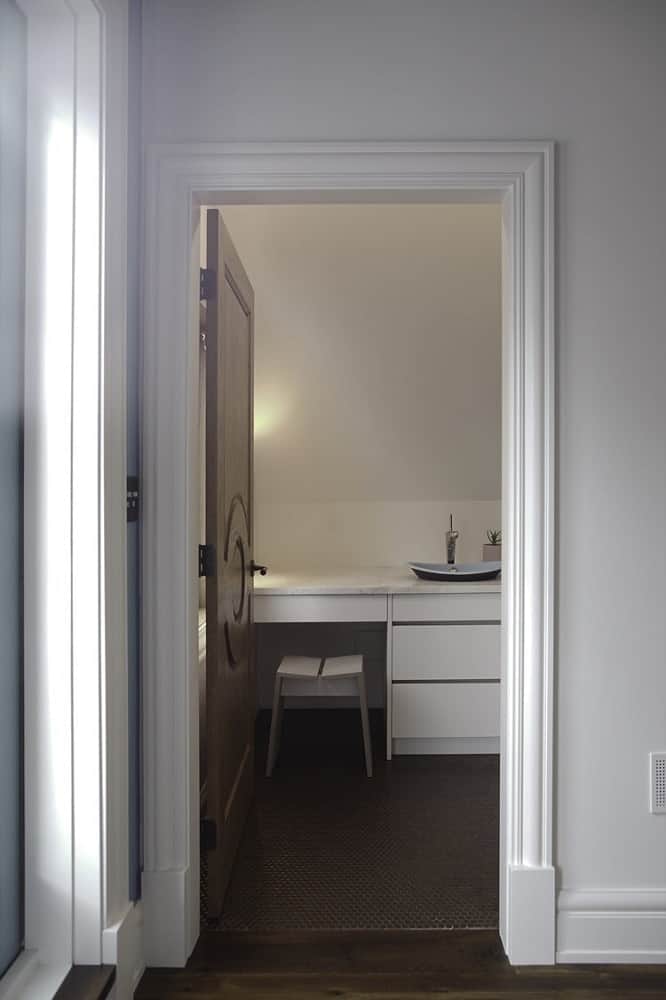 This is the private bathroom of the bedroom with a modern white vanity that contrasts the dark floor.