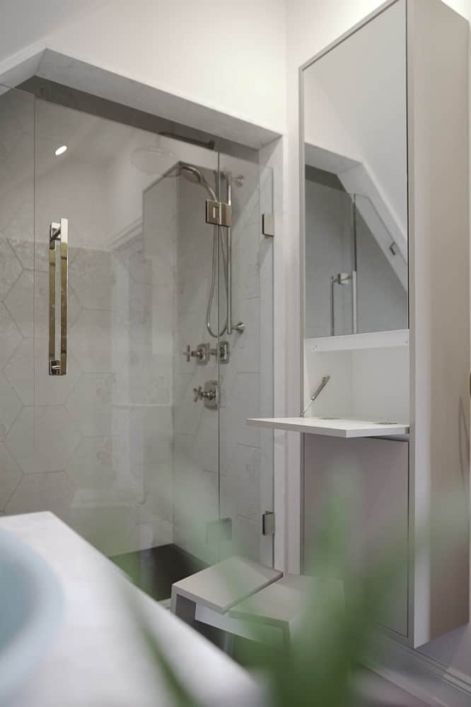 At the side of the vanity is the toilet and followed by the glass-enclosed shower area.
