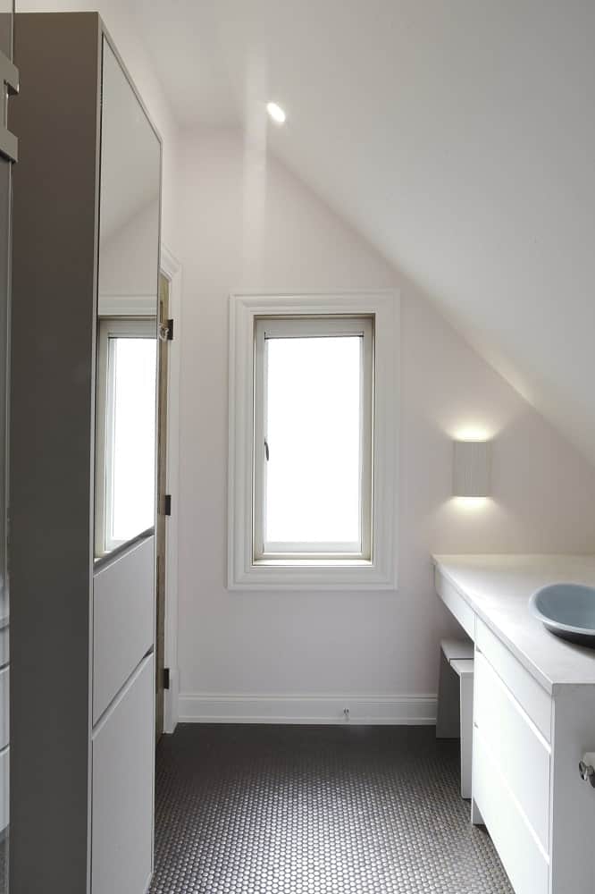 This is a view of the small bathroom from the vantage of the shower area showcasing the shed ceiling and the window on the far side.