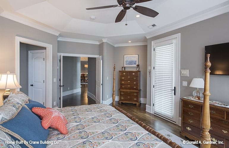 Primary bedroom with a four-poster bed, wooden dressers, and a wall-mounted TV.