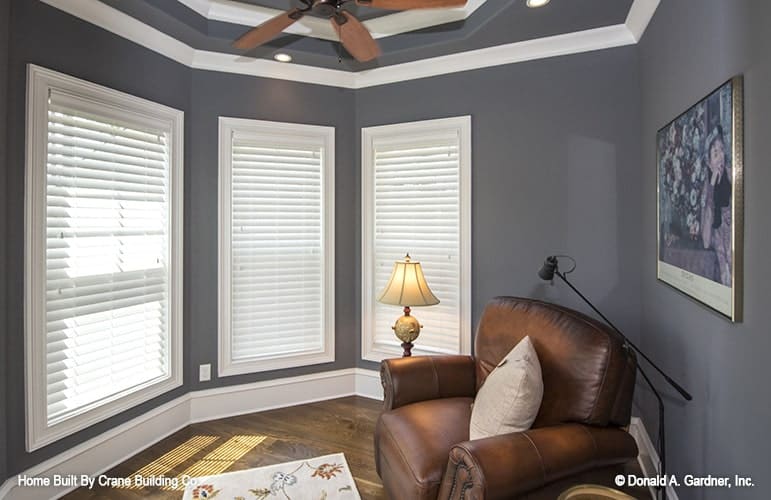 Sitting room with step ceiling, leather armchair, and gray walls adorned with a framed artwork.