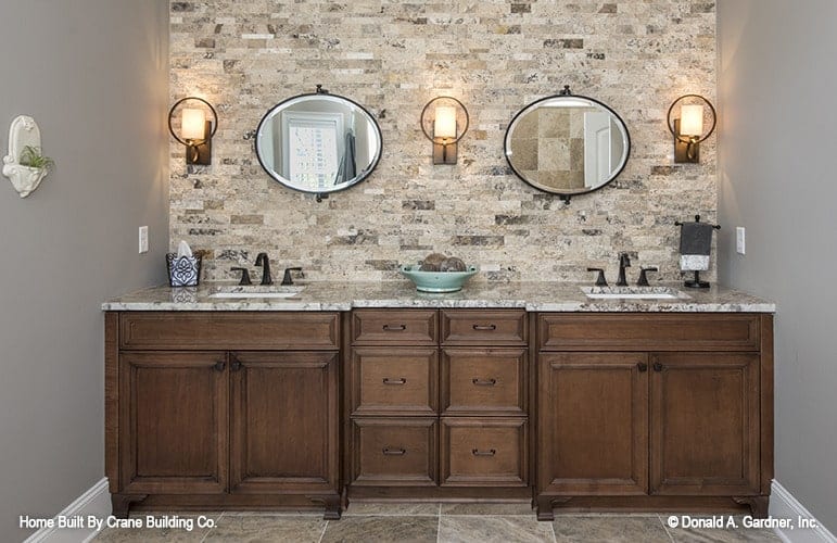 A couple of round mirrors and glass sconces sit above the dual sink vanity.