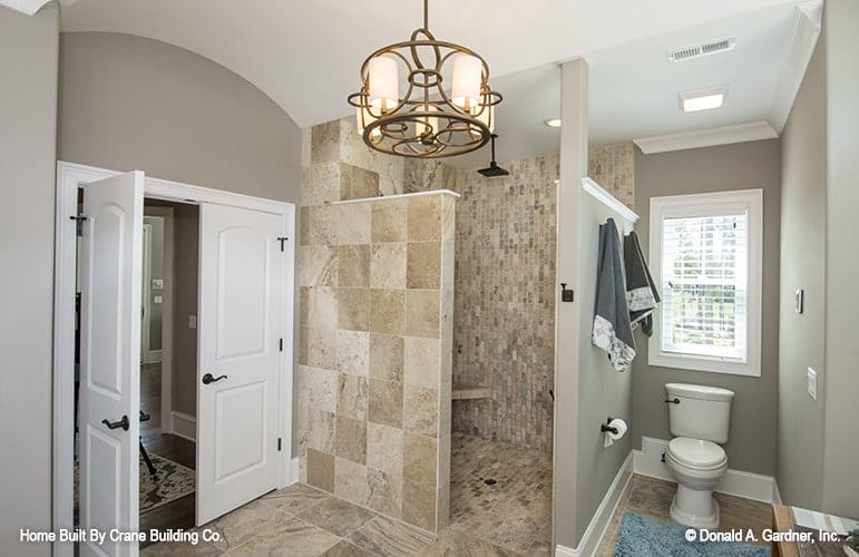 A white french door opens to the primary bathroom with a walk-in shower and a toilet area.