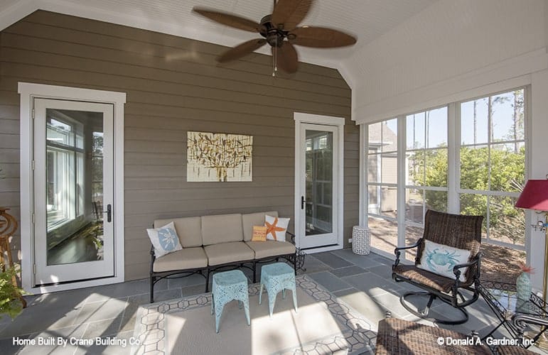 A pair of glass doors reveal the screened porch filled with wicker chairs and a cushioned sofa.