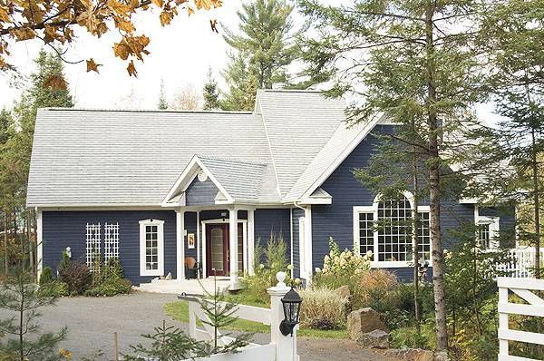 Angled front view showing the blue siding and the entry porch lined with white columns.