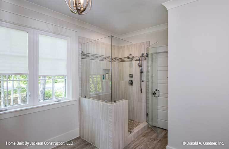 The primary bathroom features a walk-in shower with tiled walls, chrome fixtures, and a glass hinged door.