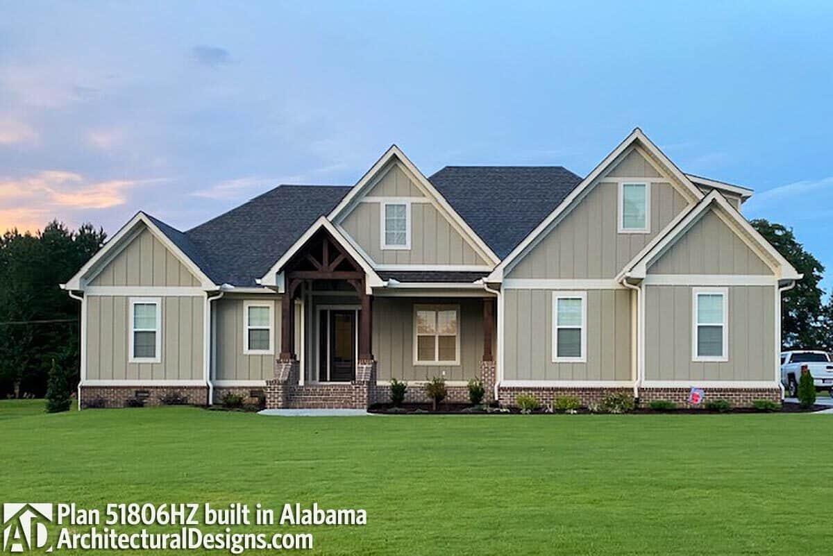 Front exterior view showing the gray board and batten siding, brick bases, and a covered porch adorned with decorative trims.