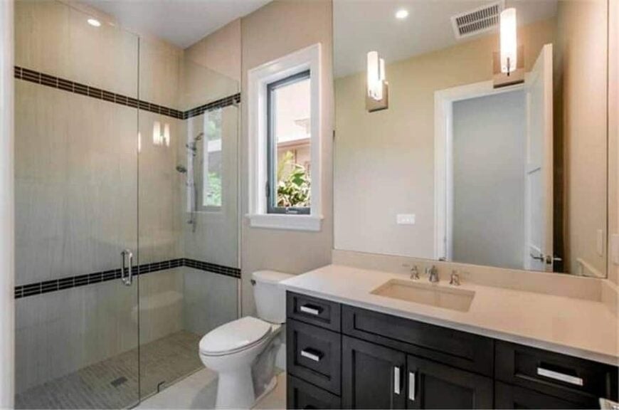 Bathroom with a walk-in shower, a toilet, and a sink vanity paired with a frameless mirror.