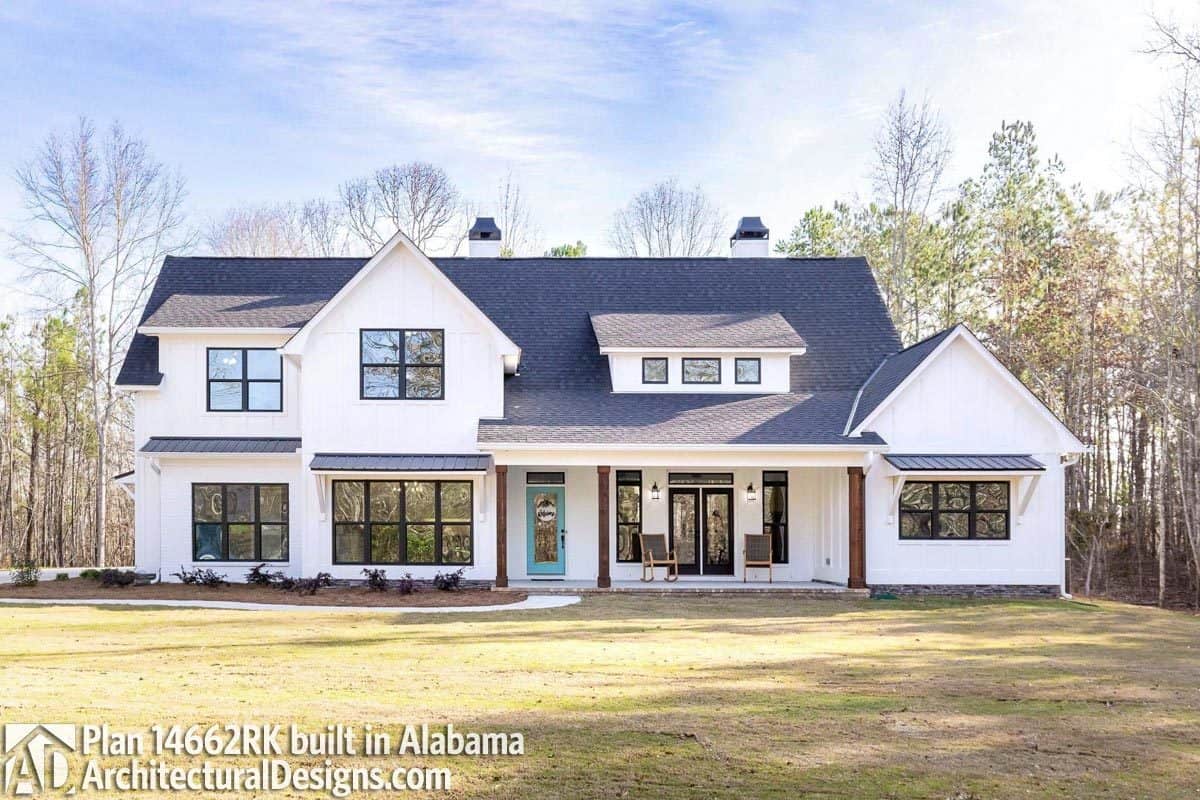 The entry porch of this house features a blue glazed front door and a large shed dormer on top.