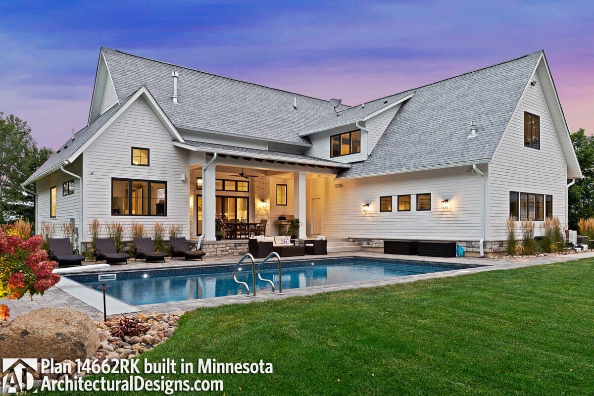 Wicker seats and loungers complement the pool while a summer kitchen and outdoor dining fill the covered porch.