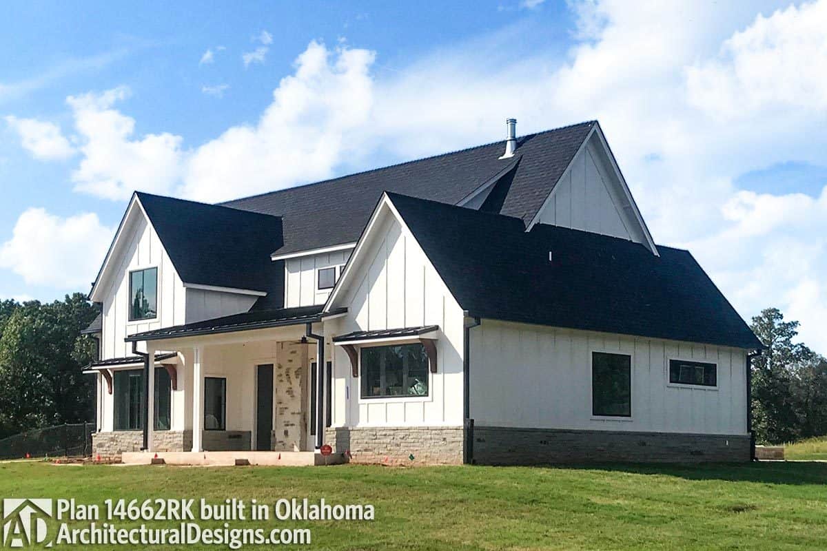 Side exterior view with vertical lap siding, stone bases, and metal awnings.