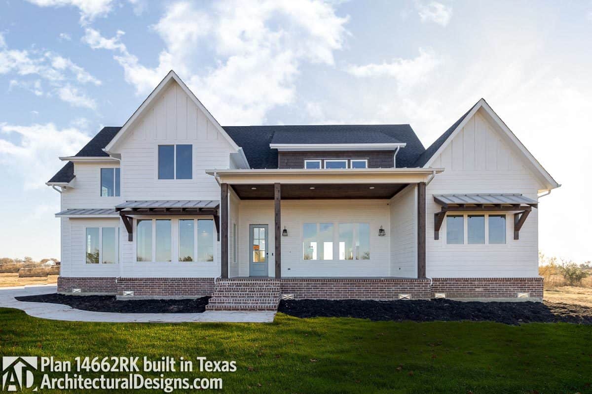 Red brick bases and rustic columns contrast the pristine white siding of the house.