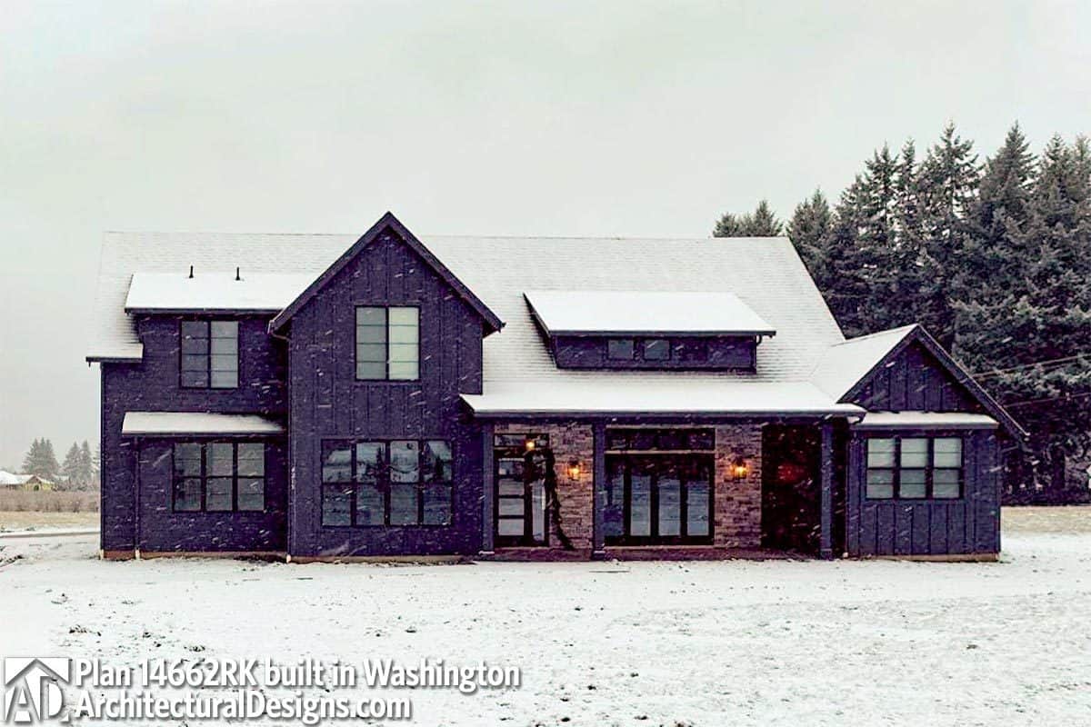 The home's dark exterior accentuated with bricks stands out against the snow.