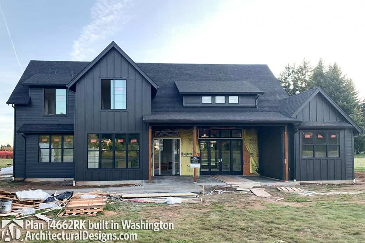 The home showcases a black exterior softened by wooden columns.