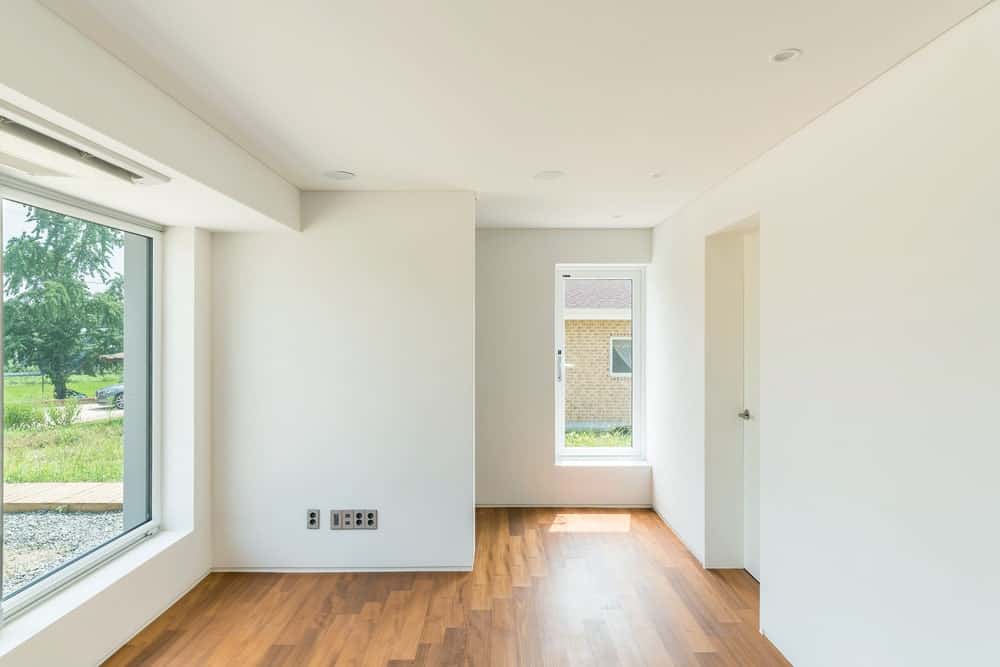 The bright beige walls and ceiling of the living room are brightened and augmented by the natural lights coming in from the glass walls.