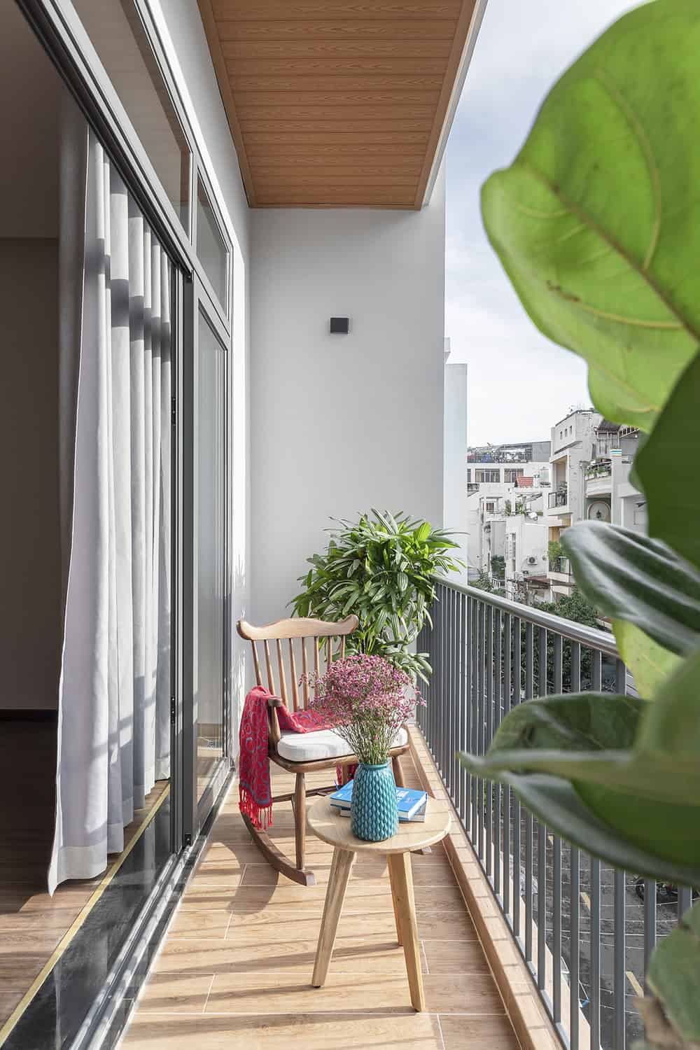 This view of the balcony showcases the size of the area that can only fit one wooden chair and a wooden coffee table.
