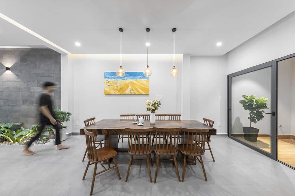 Across from the cabinetry of the kitchen is this dining area that has a wooden dining set that stands out against the gray concrete flooring.