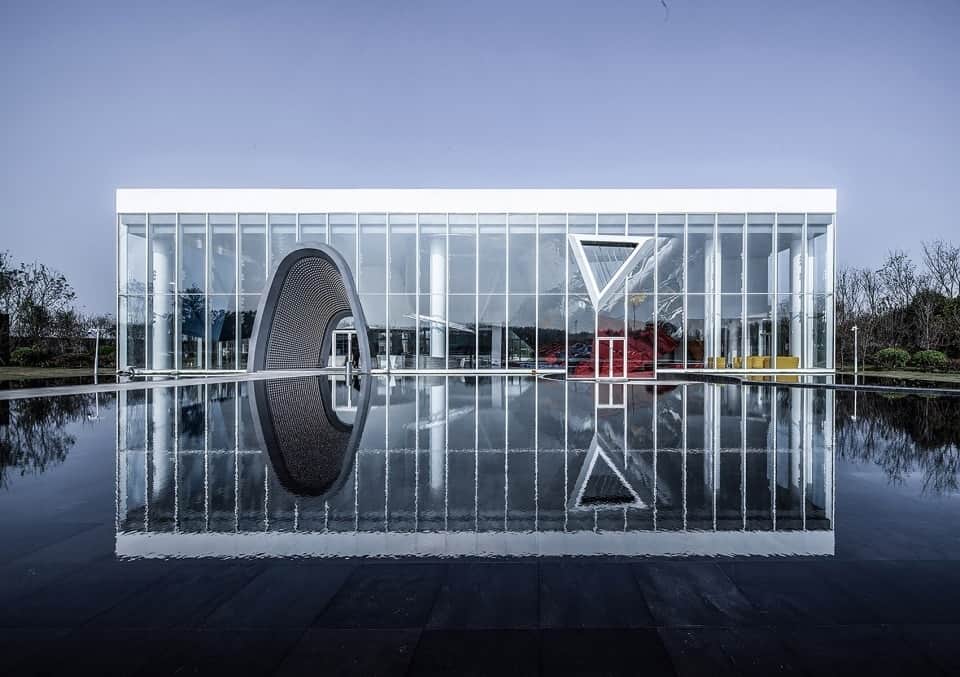 This is a full view of the building in daytime showcasing the unique structures and glass walls that are reflected on the water landscape.