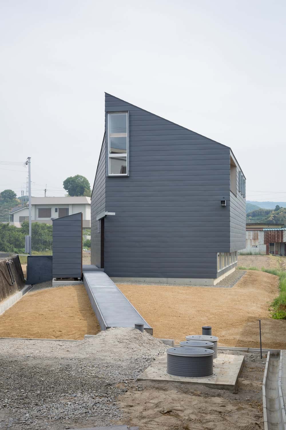 This is a view of the side elevation of the house showcasing more of the gray exterior walls paired with small windows.