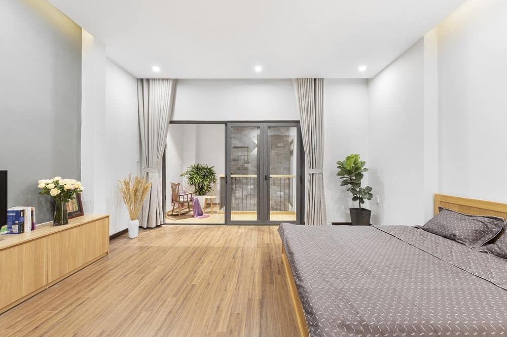 The set of glass doors lead to the spacious bedroom with hardwood flooring that blends with the cabinet across from the bed.