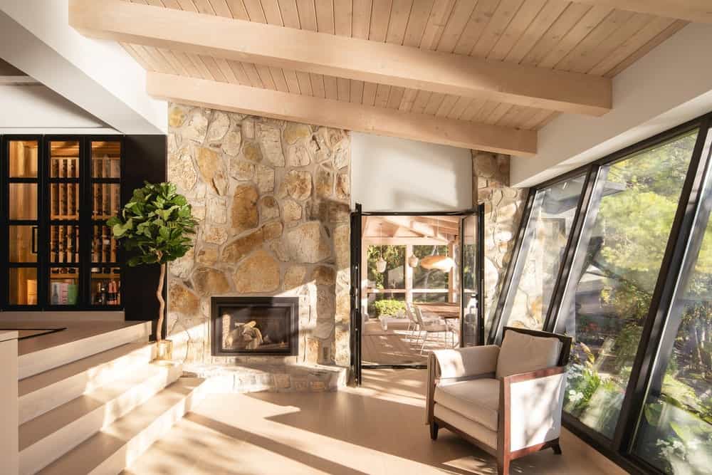 Upon entry of the glass doors of the porch, you are welcomed by this cozy interior that has stone walls, a fireplace and a comfortable cushioned arm chair.