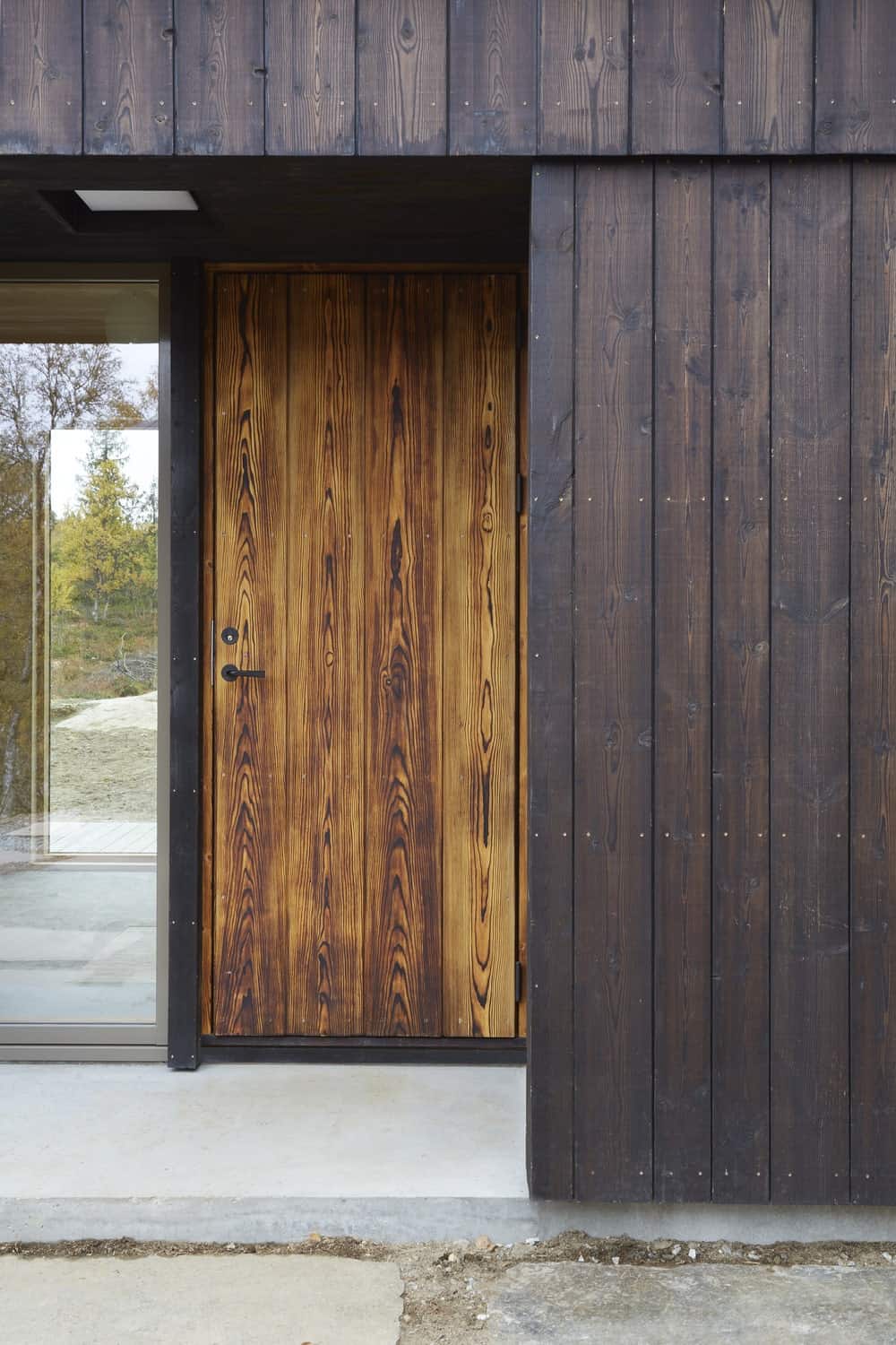 This is a close look at the main door of the house with a slightly lighter tone and a large glass panel on its side to let in natural lighting.