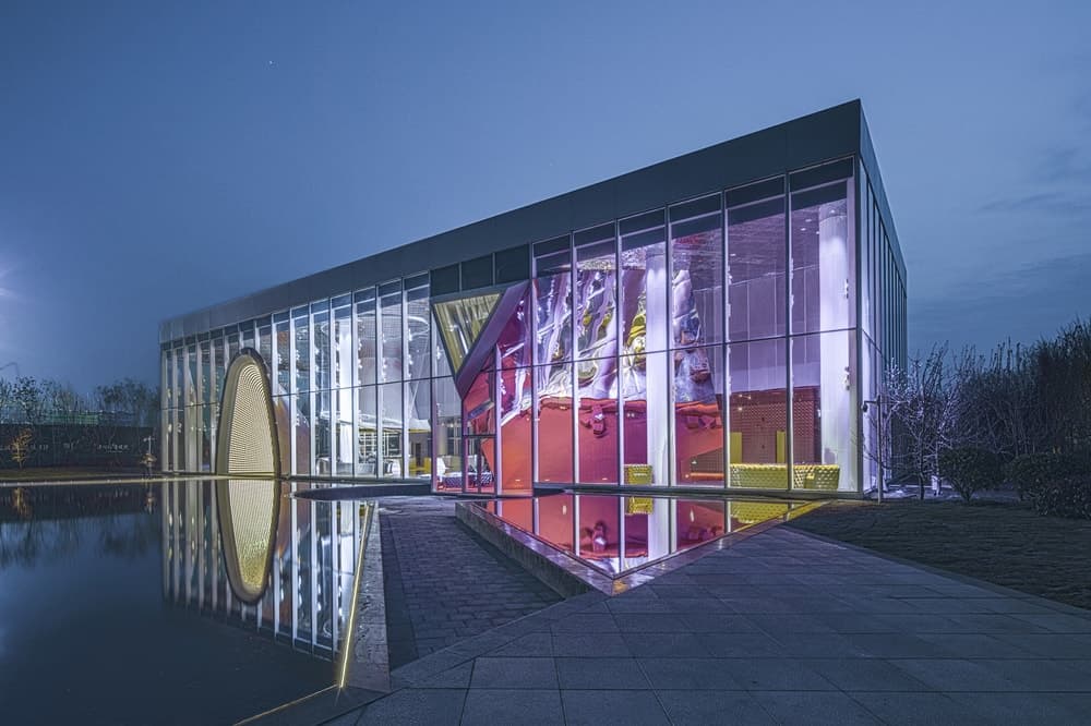 This is a look at the building during nighttime showcasing the colorful elements that pair perfectly with the unique structures. These are then doubled as they are reflected.