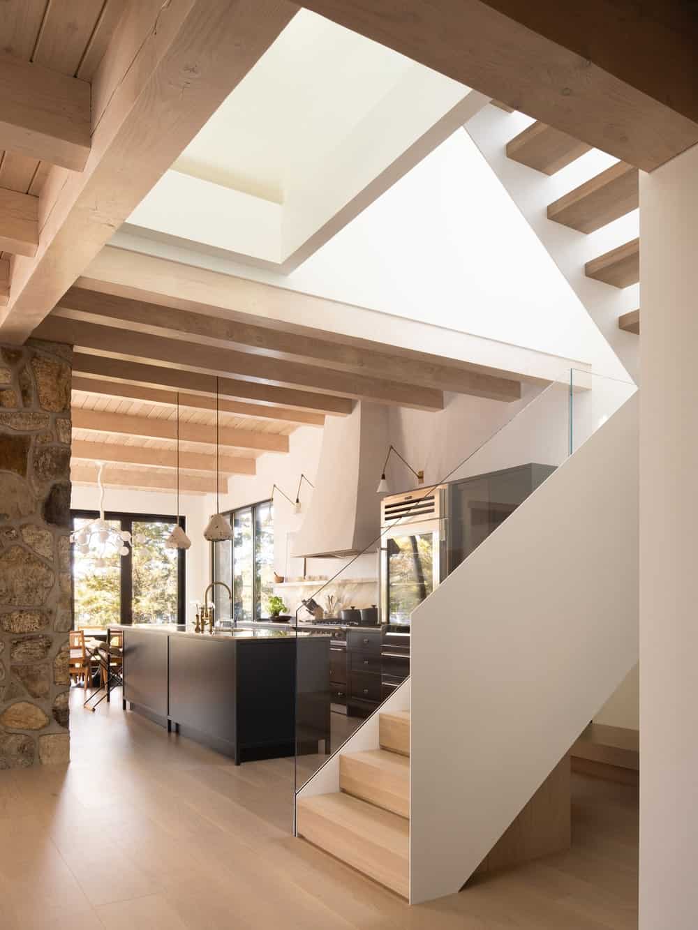 A few steps from the dark kitchen island is the staircase with wooden steps to match the hardwood flooring and the walls to match the rest of the house interiors.