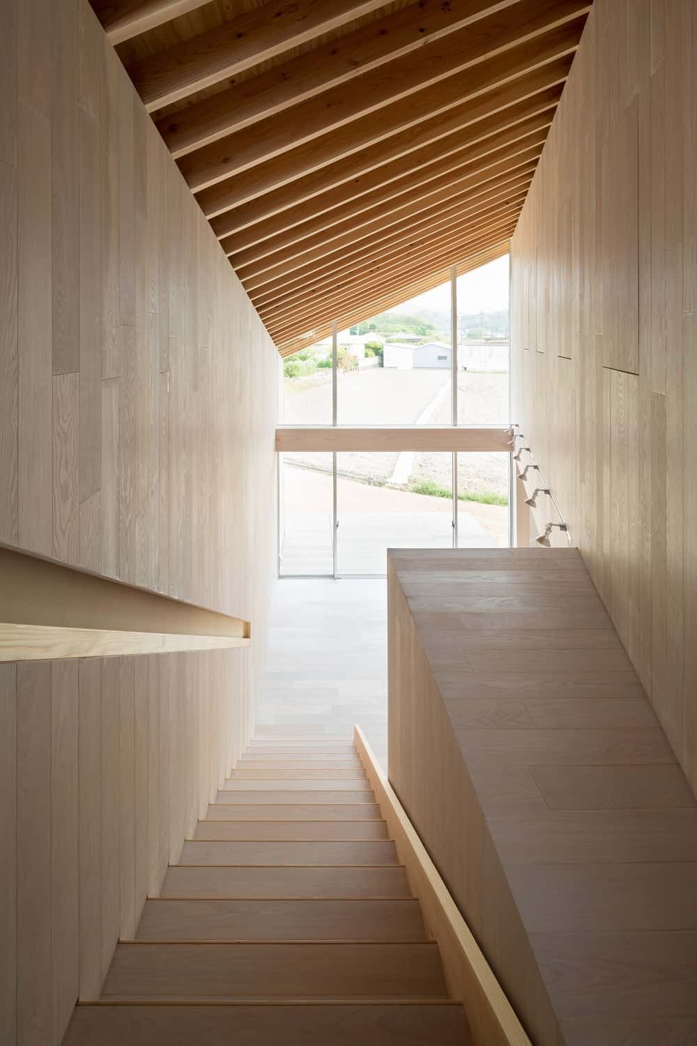 This is a look at down the staircase with the same wooden tone as the rest of the interiors. It has a wall depression that works as the banisters.