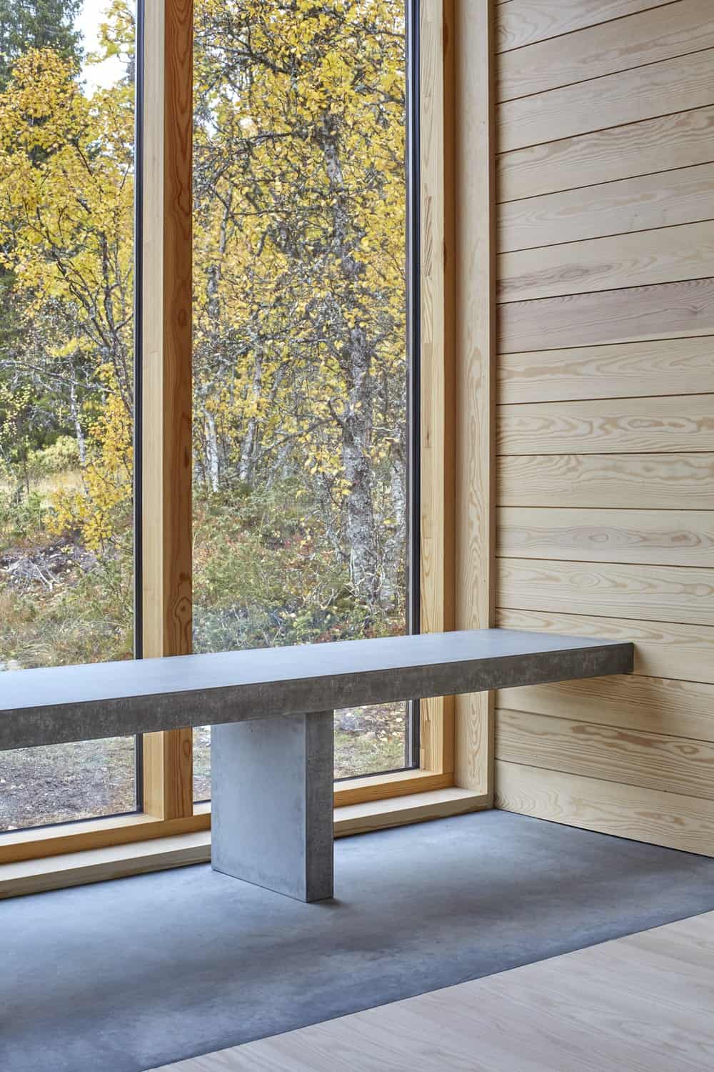This corner of the house has a built-in stone bench that pairs well with the flooring and gives a nice complement to the glass wall and wooden wall.