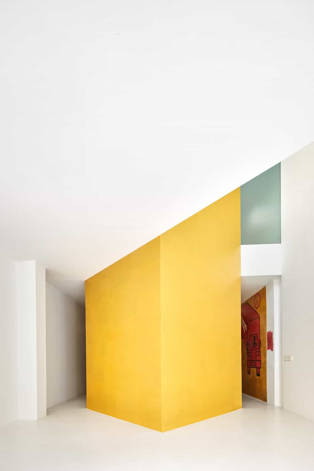 This is a close look at the large yellow structure that houses the staircase as viewed from the living room area that has a tall white ceiling.